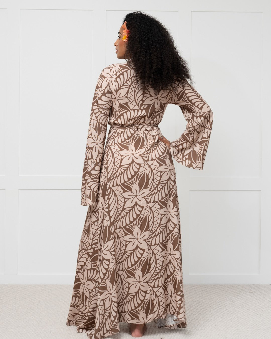 Woman wearing a long, patterned dress against a white background