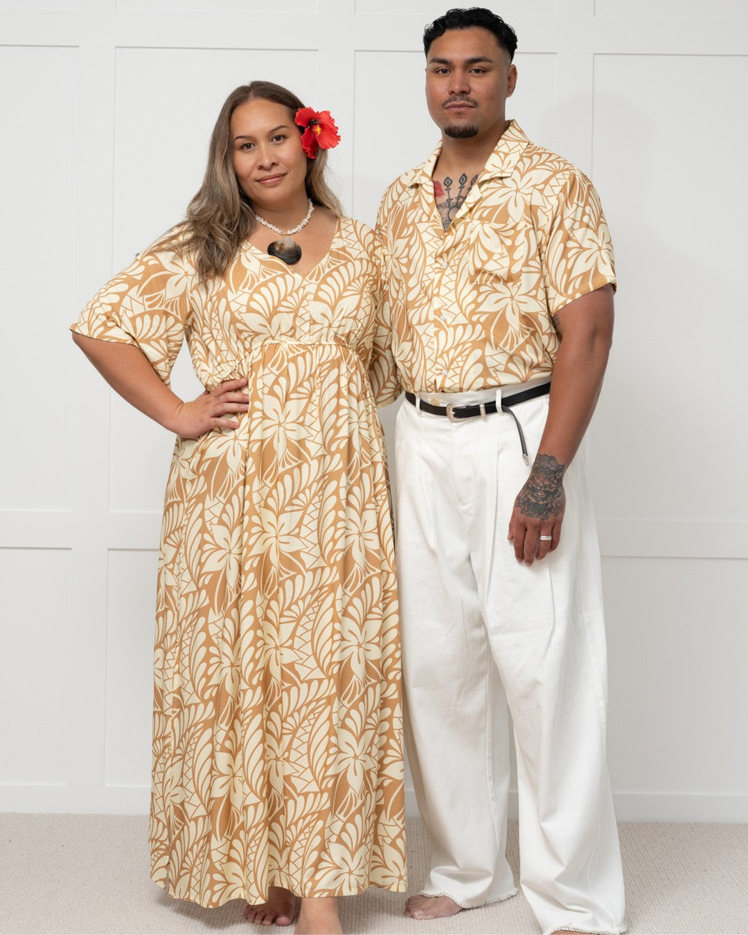 Two people wearing matching tropical outfits against a white background