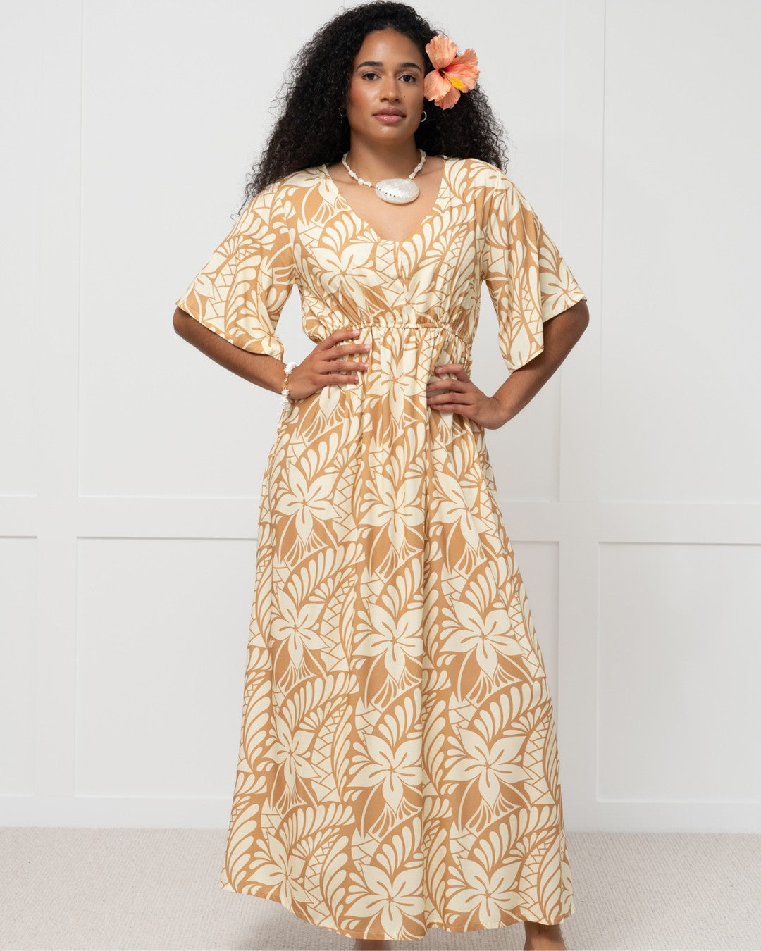 Woman wearing a long, patterned island dress against a white background