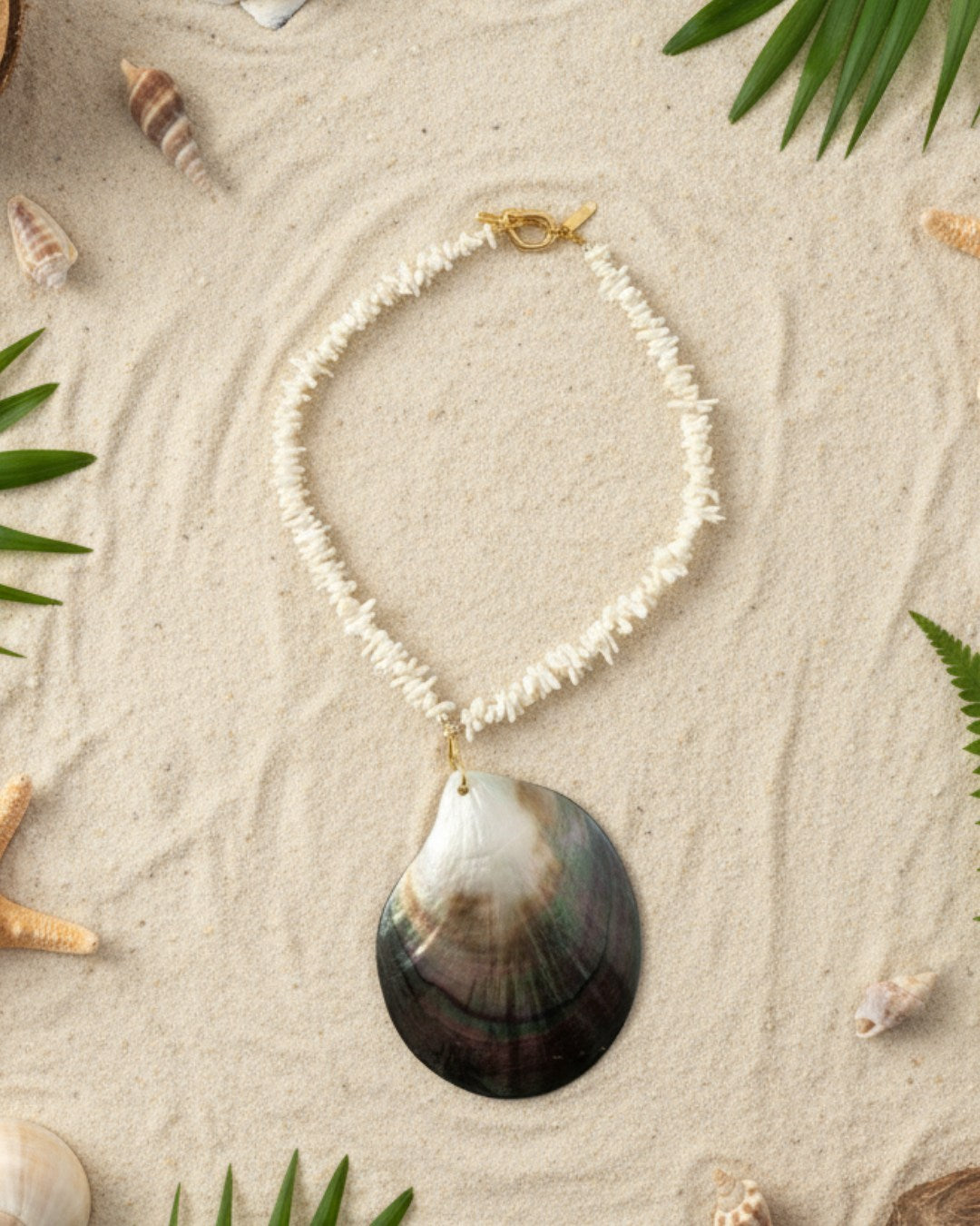Necklace with a shell pendant on a sandy background with shells and leaves.