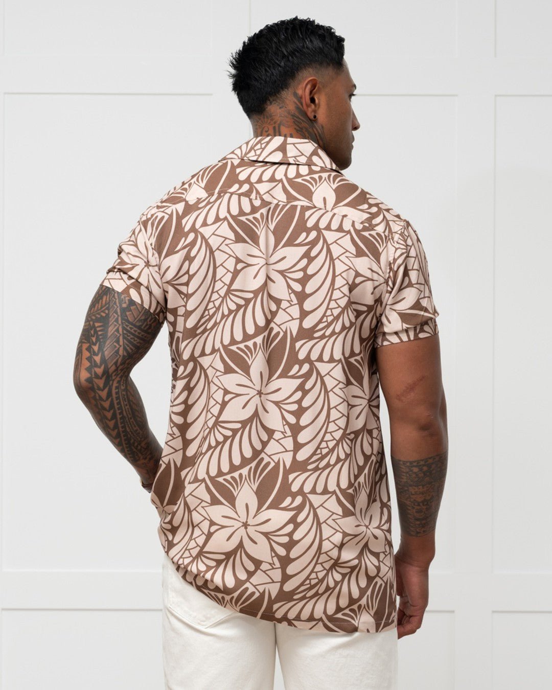 Man wearing a brown floral-patterned island shirt against a white background